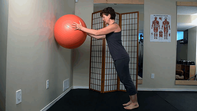 A woman performs a wall plank using a stability ball to increase core engagement and balance