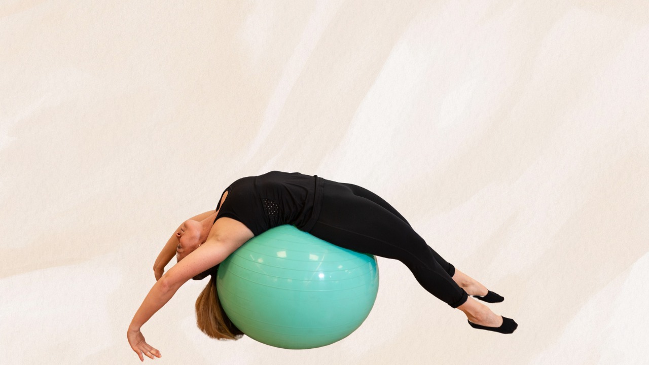 Woman lying back on a teal stability ball, stretching her core during a Pilates workout
