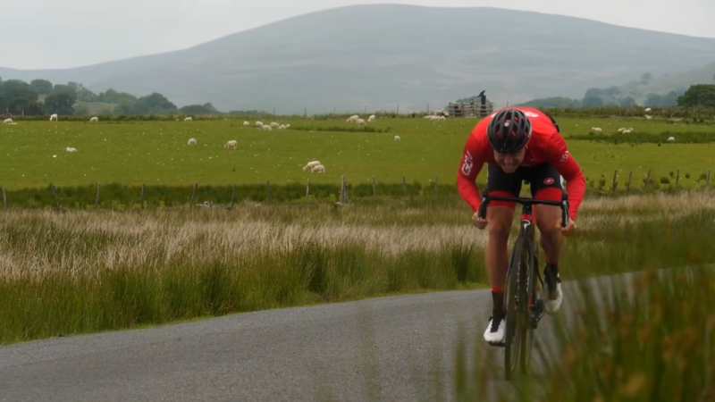 A Cyclist in A Red Jersey Rides Intensely on A Rural Road