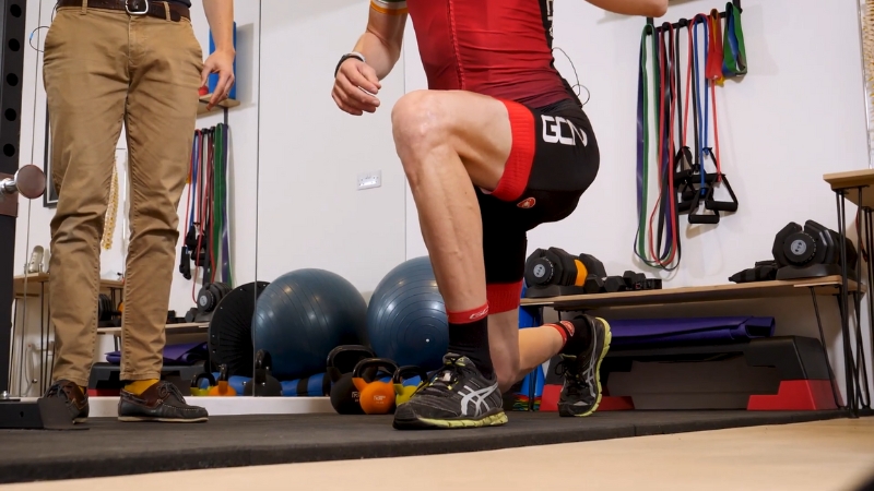 Cyclist Performing a Lunge Exercise Under Supervision to Address Knee Pain from Cycling