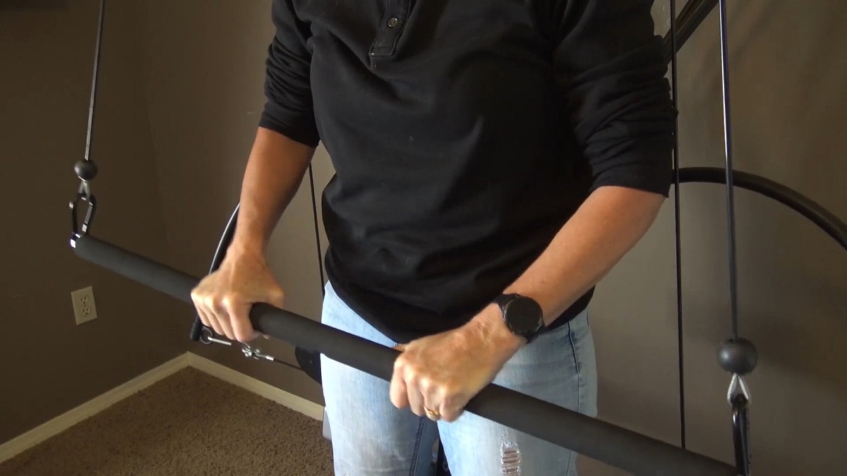 Person gripping a Bowflex resistance bar indoors during a workout