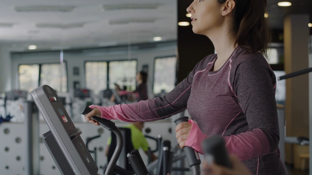 Woman using an elliptical trainer in a modern gym environment