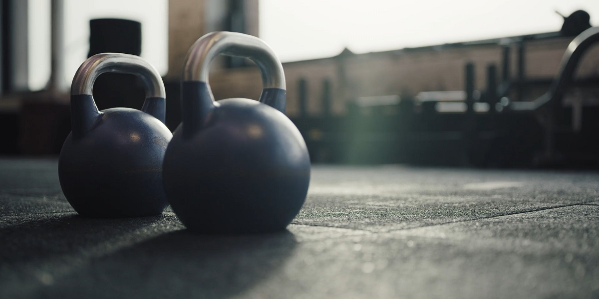 Pair of kettlebells placed on a gym floor, with blurred gym equipment in the background