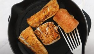 Crispy fish fillets sizzling in a hot pan