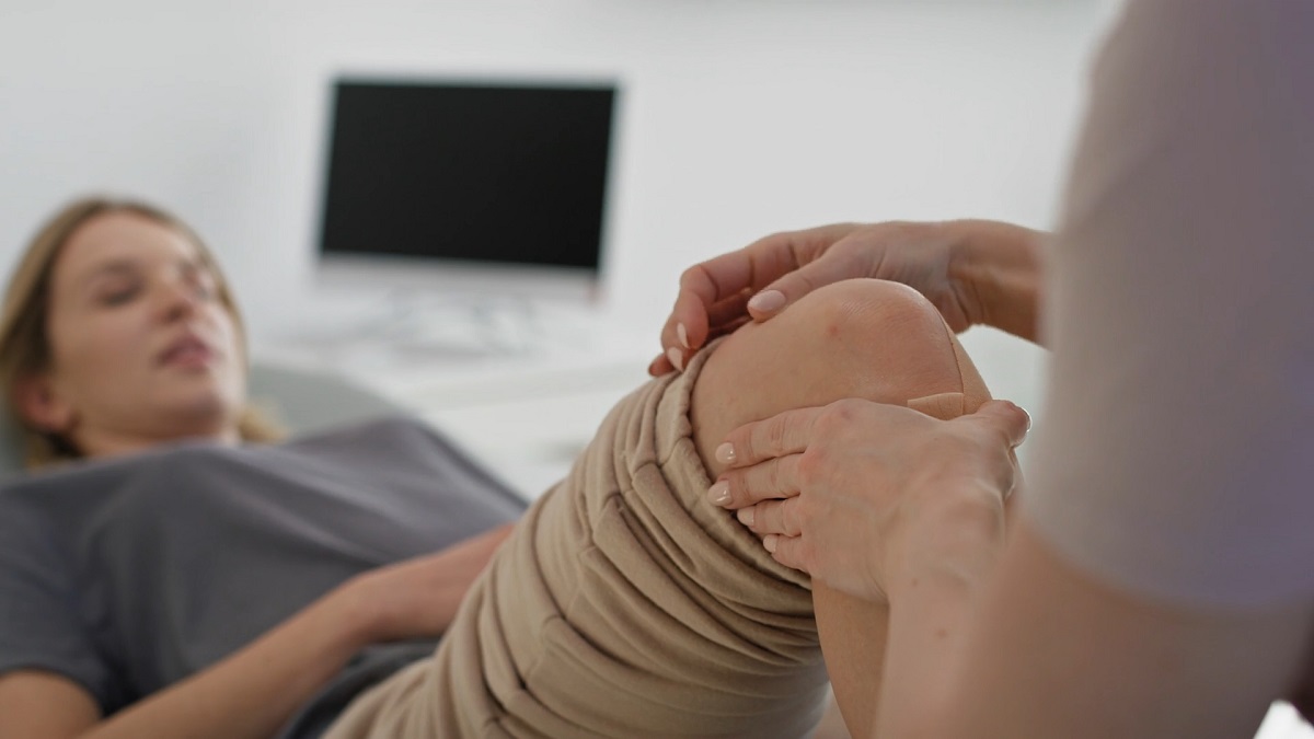 A healthcare professional gently holding and assessing a patient's knee in a clinical setting