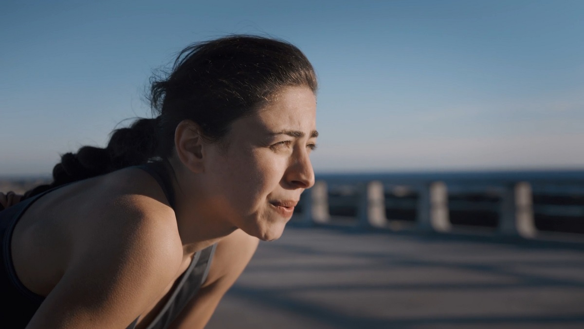 A woman taking a break after exercise, looking pensive and focused, allowing herself to process emotions