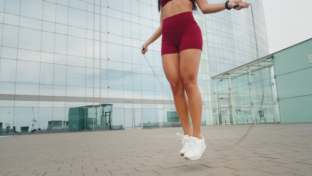 A close-up of a woman in red workout shorts skipping rope