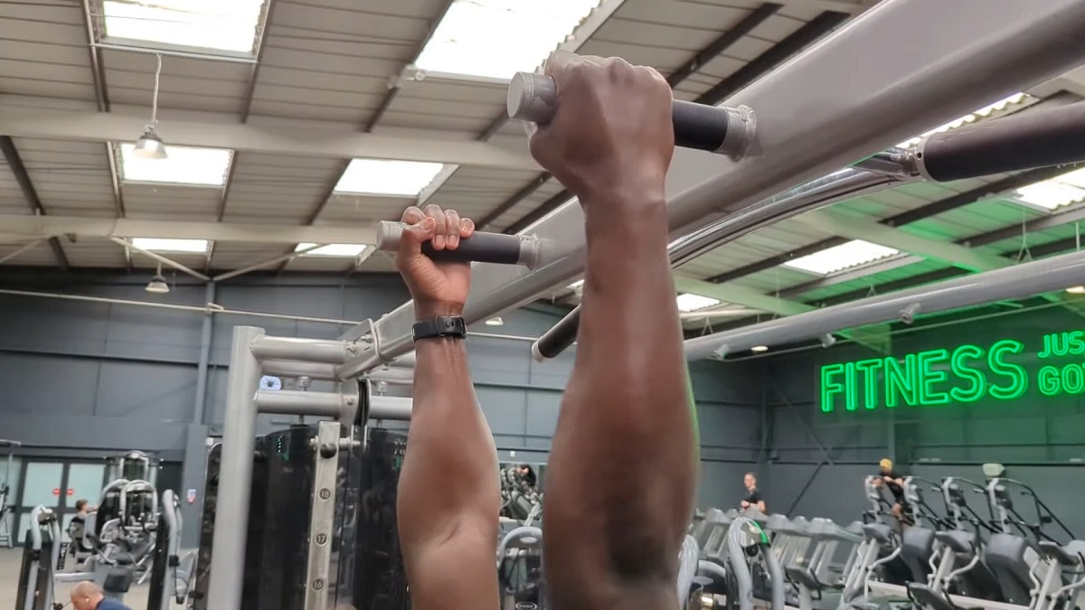 Close-up of a person gripping a pull-up bar at a gym, highlighting upper body strength training