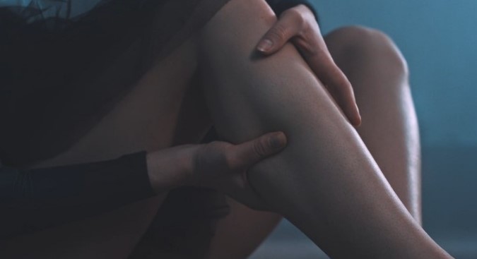 Women holds her leg in pain