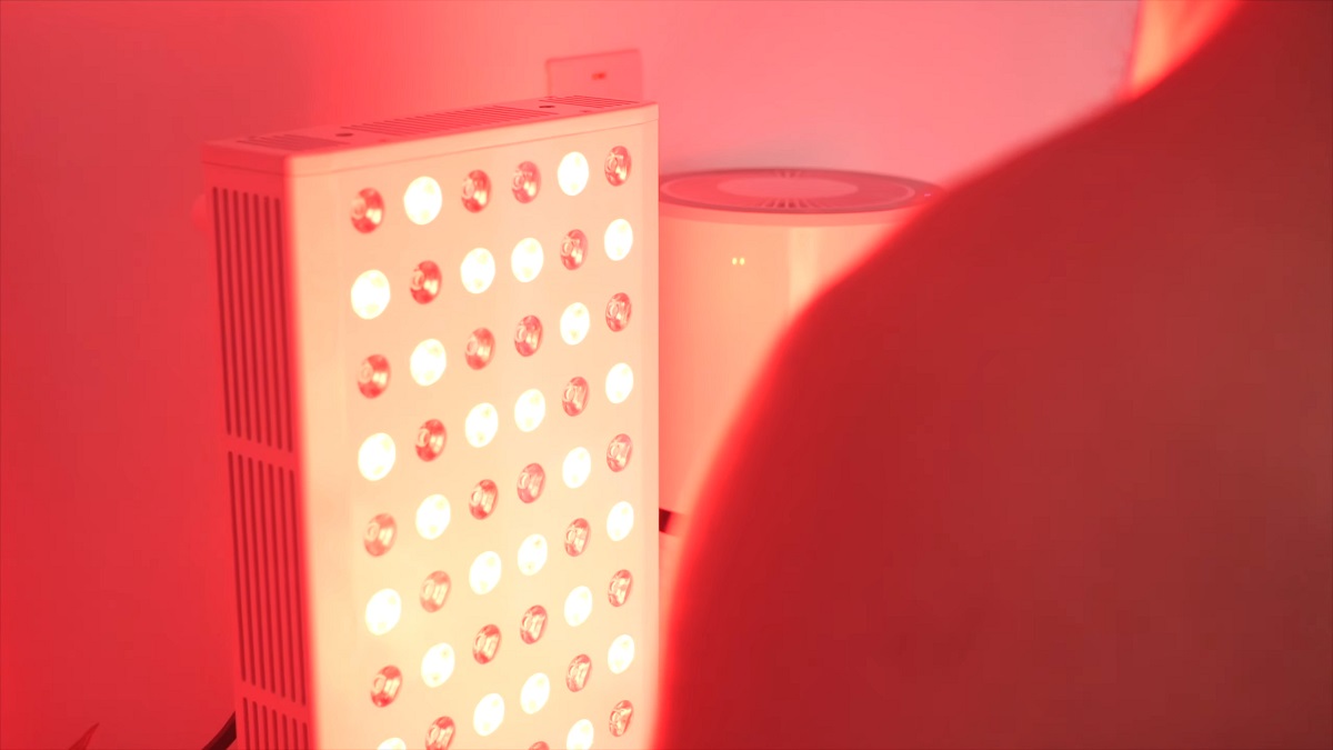 A person undergoing red light therapy with a bright LED panel emitting red light