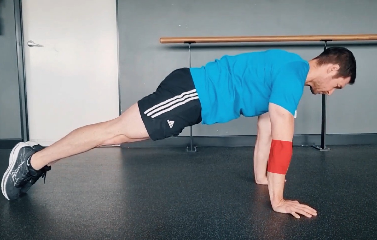 A man doing a plank exercise with an arm brace, demonstrating a core workout while managing forearm strain