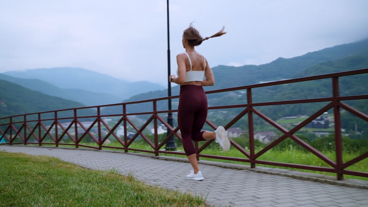 A fit woman jogging outdoors on a paved path