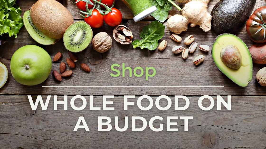 Assorted fruits, nuts, and vegetables on a wooden table with text “Shop Whole Food on a Budget.”