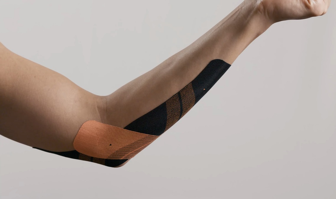 Close-up of an arm with kinesiology tape applied, providing support for muscle recovery and injury prevention, particularly for elbow pain relief