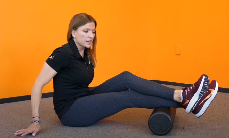 Woman stretches her legs, using a foam roller