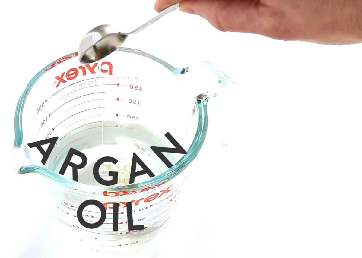 Argan oil being added to a measuring cup for DIY texturizing spray