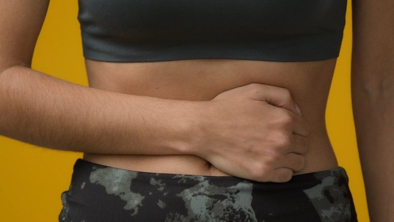 Woman holding her stomach due to discomfort, highlighting how creatine cause constipation in some users