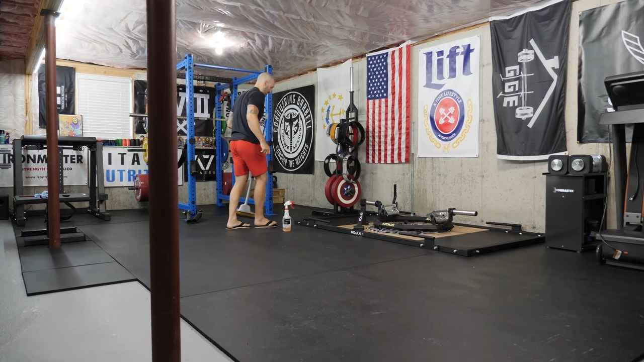 Man cleaning the floor of a home gym with weights and equipment around