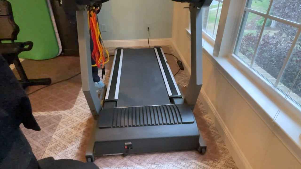 Home treadmill placed near a window in a carpeted room