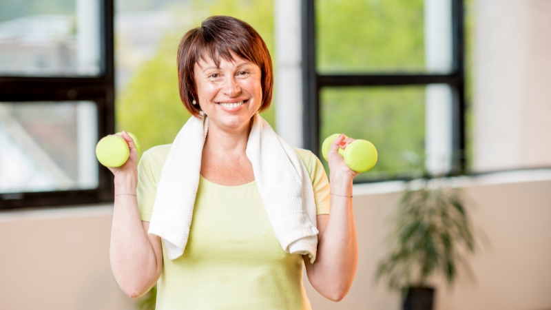 Woman holding dumbbells, exercising and enjoying working out after 50
