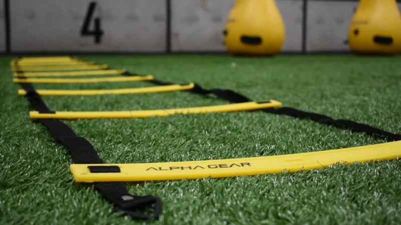 An agility training ladder set up on turf with yellow markers ready for speed drills
