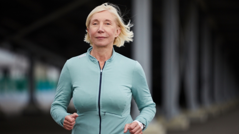 Woman jogging outdoors, pacing herself during a workout after 50