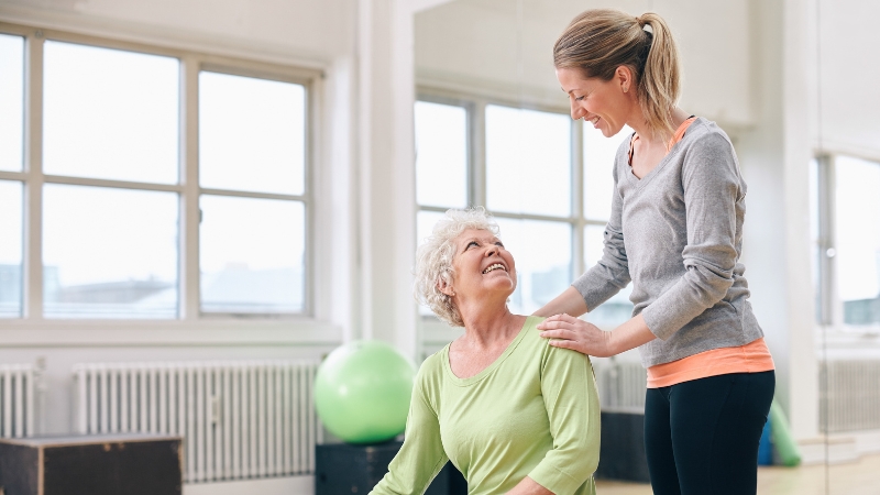 Trainer helping a woman with her workout, encouraging variety in routines after 50