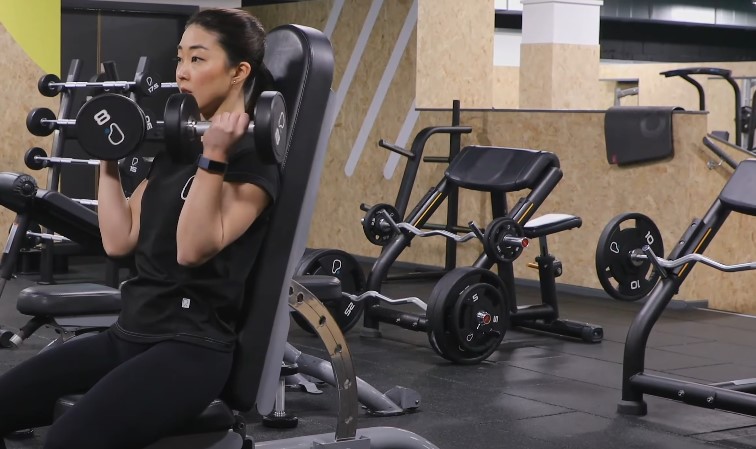 Gym setting with a woman lifting weights