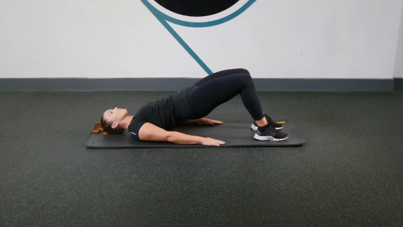 A person performing glute bridges to strengthen the hips and relieve lower back tension