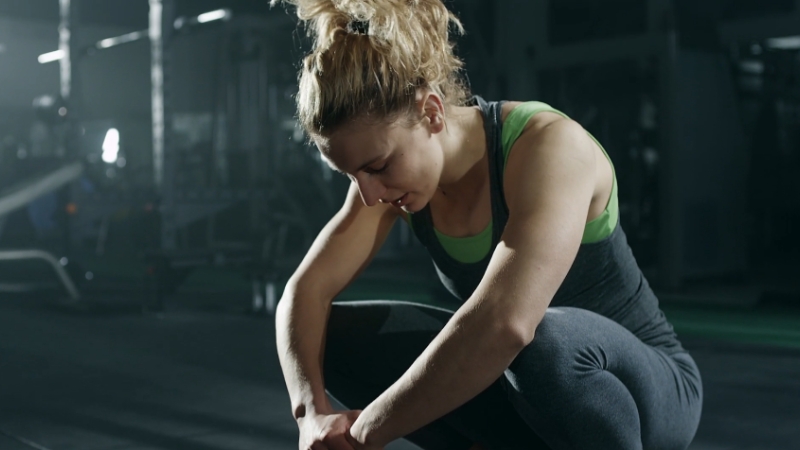 Woman resting in the gym, showing signs of workout fatigue
