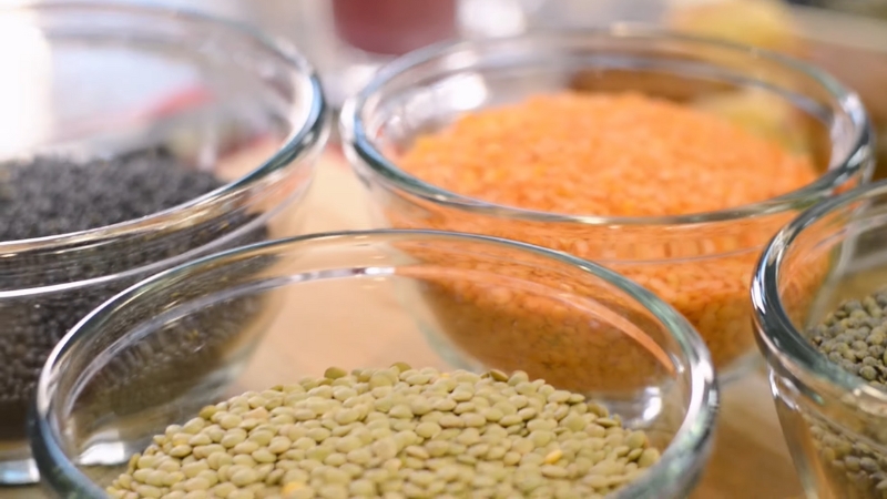 Bowls of green, red, and black lentils arranged on a kitchen counter as a fiber-rich food option