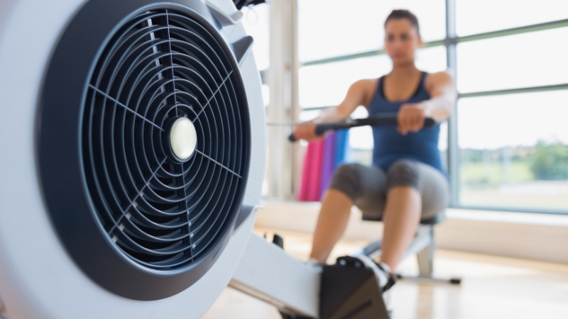 Woman using a rowing machine indoors, highlighting low-impact cardio for heart health and muscle strength