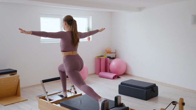 Woman doing pilates on a reformer machine, focusing on low-impact strength and balance
