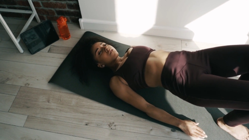 Woman lying on a yoga mat, focusing on recovery and mobility exercises
