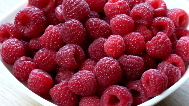 A bowl filled with fresh, ripe raspberries, known for their high fiber content and digestive benefits