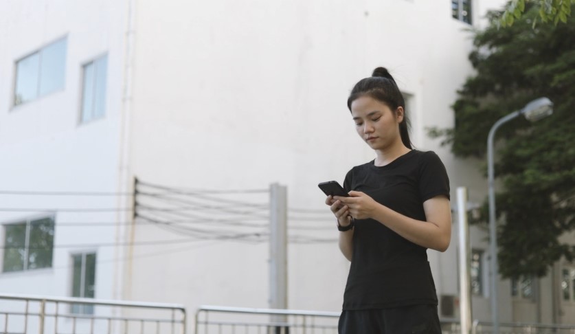Young woman engrossed in a mobile device outdoors
