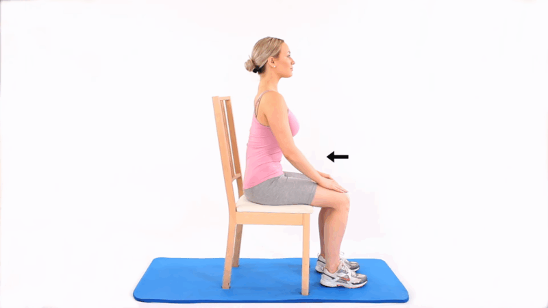 A person performing seated pelvic tilts on a chair