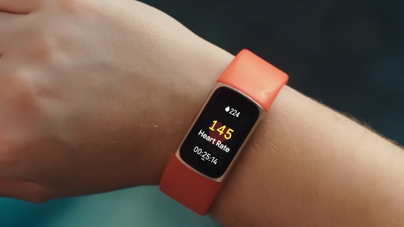 A red smart GPS fitness watch showing heart rate and workout time during outdoor training