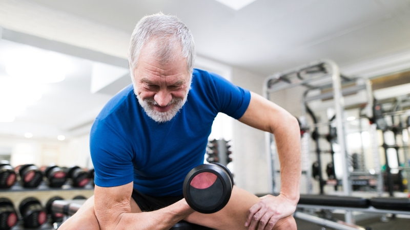 Older man lifting a dumbbell during a strength training session at the gym