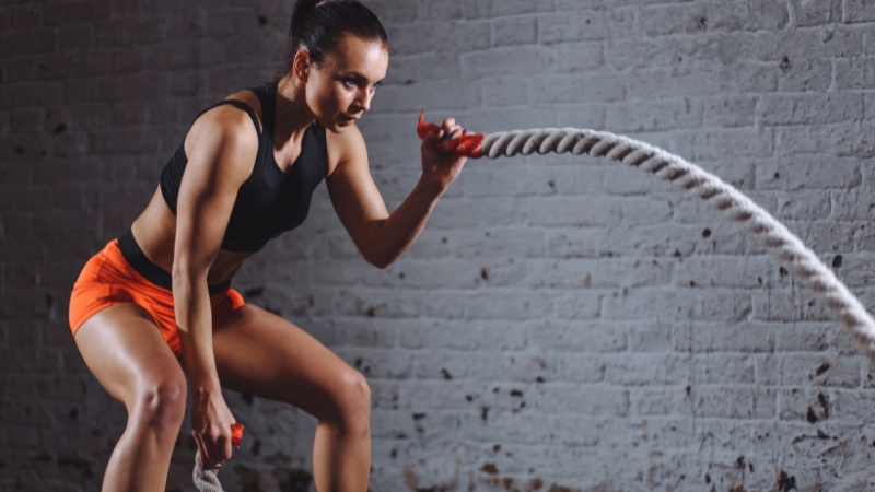 A woman using battle ropes during a workout at Miami Athletic Club
