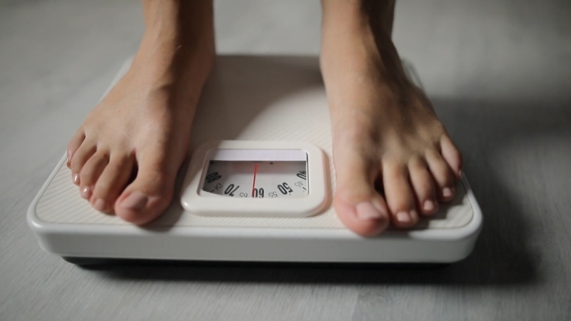 A person standing on a scale to track their progress after reaching their weight loss goal