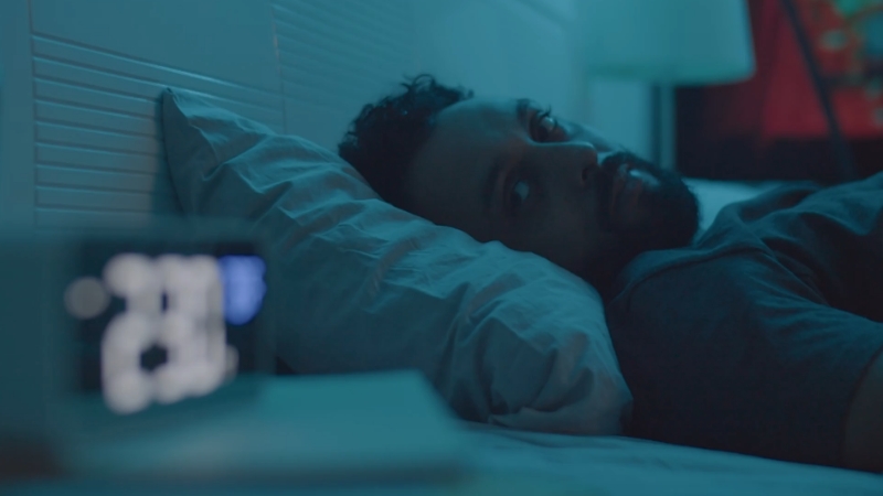 A person lying awake in bed, staring at the clock in the middle of the night