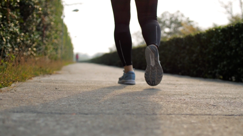 Person walking on a paved path, showing a low-impact cardio option for knee support