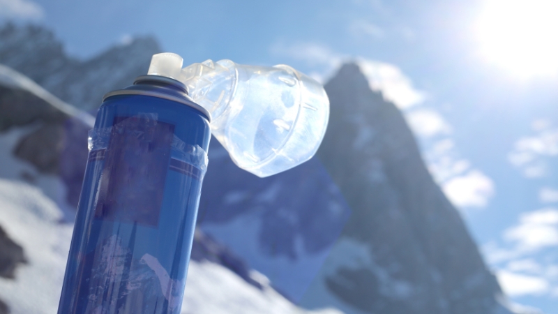 Portable oxygen canister with mask shown in a snowy high-altitude setting, used as safety gear for mountain treks