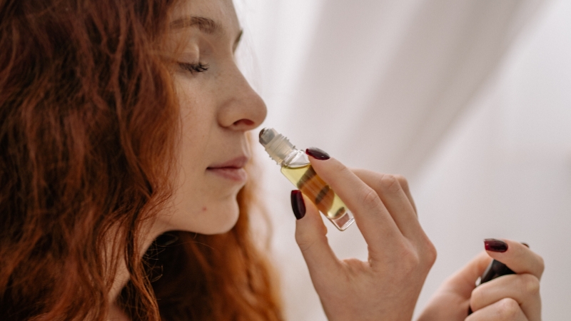 Woman applying essential oil to her skin with a roller bottle during an aromatherapy session