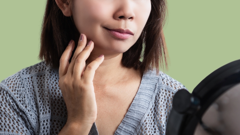 Woman touches her face while checking for Bell's Palsy signs in the mirror
