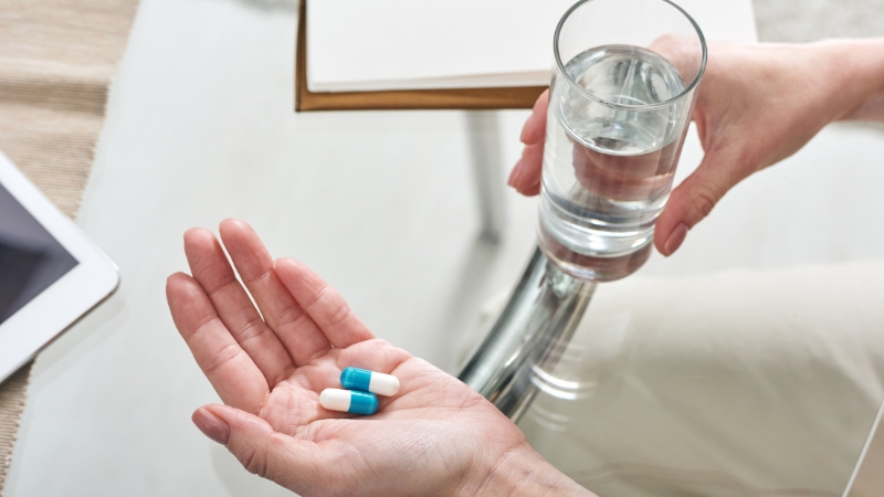 Person holding pills and water, showing beta-blockers used before activity