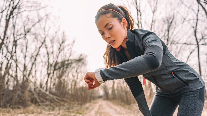 Woman checking her smartwatch on a forest trail