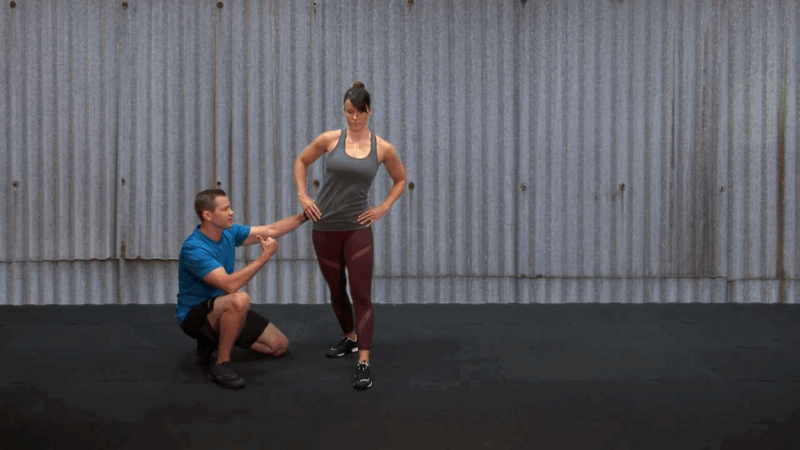 A trainer coaches a woman through a stability-focused movement during a corrective exercise session