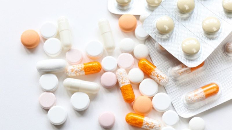 Mixed pills and capsules on a white surface, showing common forms of corticosteroids used in medical treatment